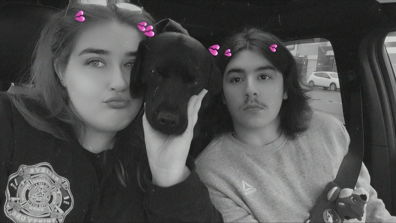 Savannah and Axel in the car with their black dog between them