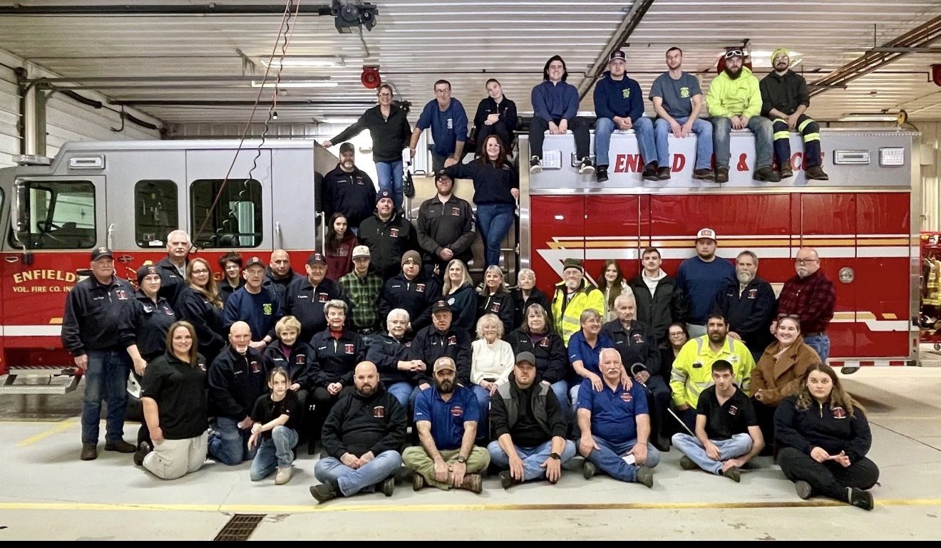 The Enfield Volunteer Fire District posing in front of their fire trucks