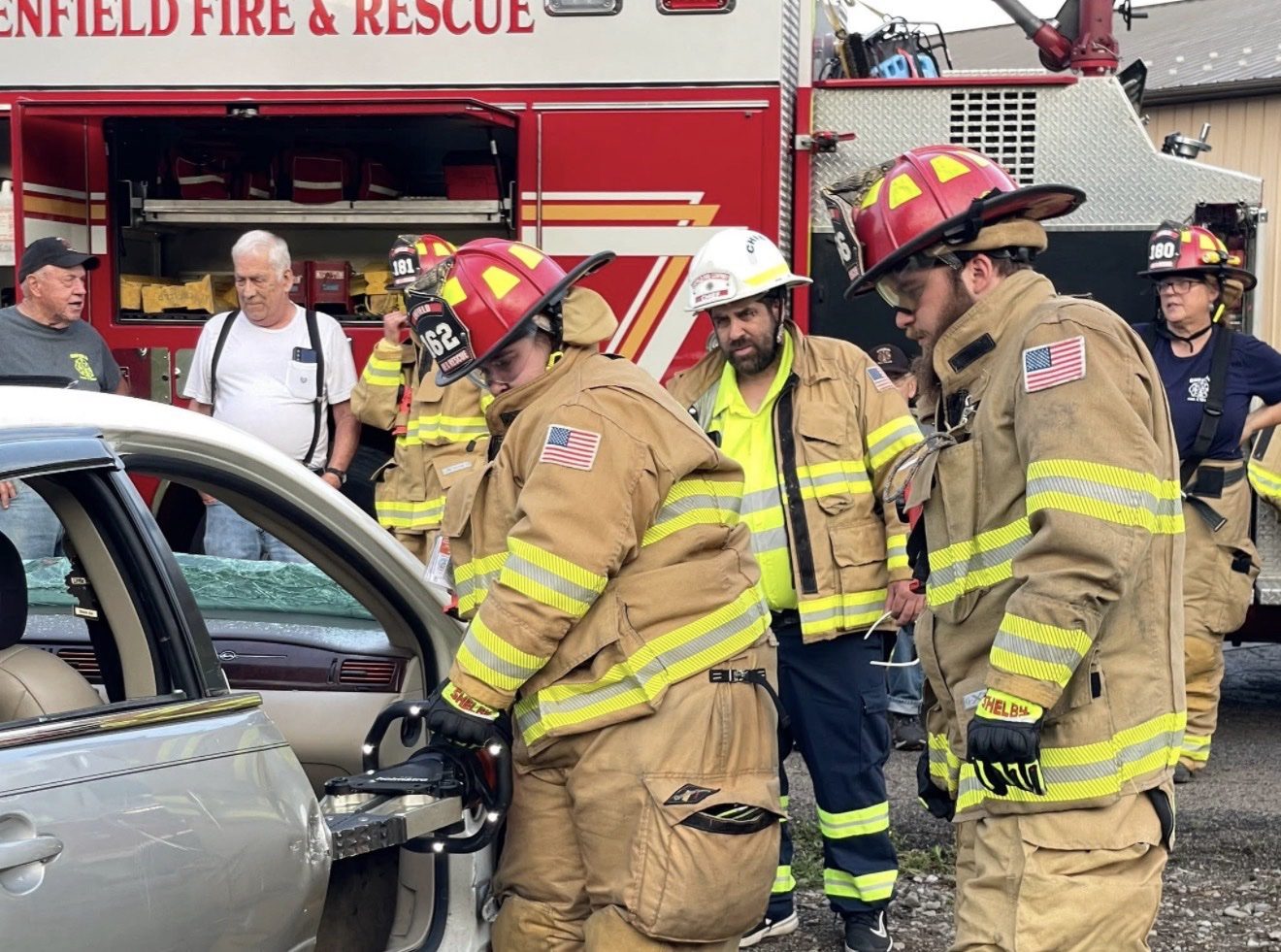 Firefighters practicing a car extrication drill in front of an Enfield Fire and Rescue truck