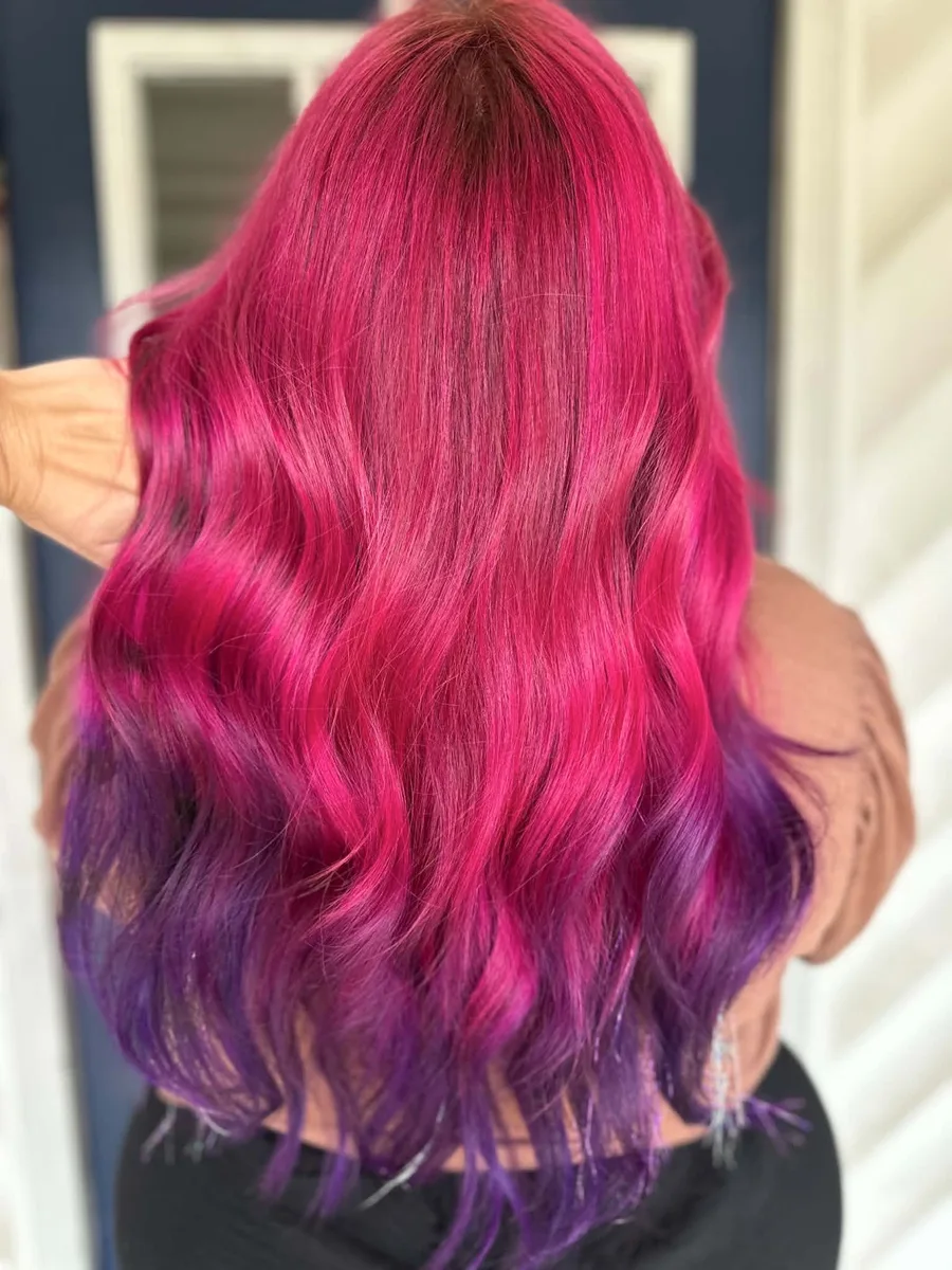 Long wavy hair in a magenta to purple ombre