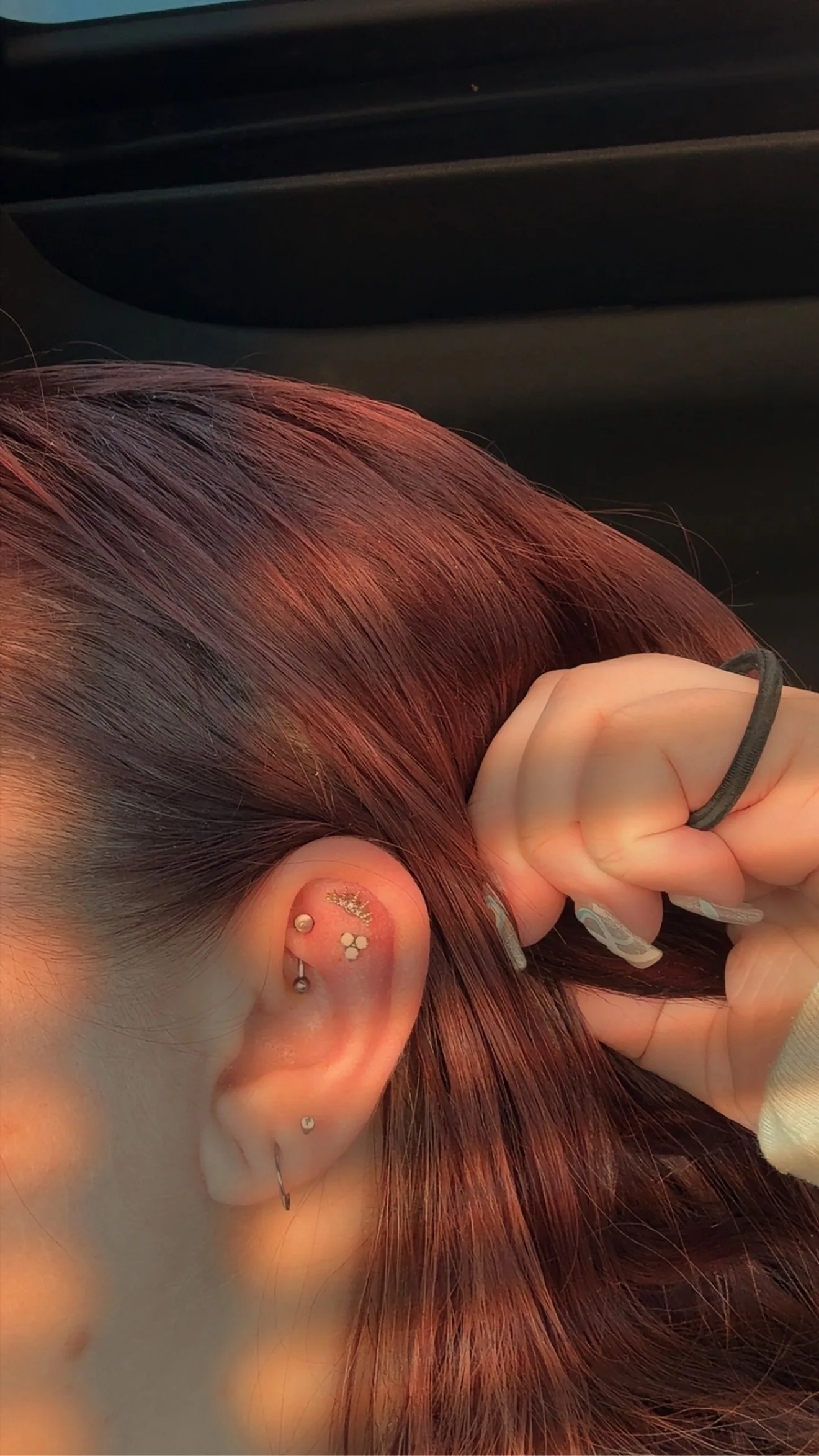 Close-up of an ear with gold flat-helix, rook and lobe piercings