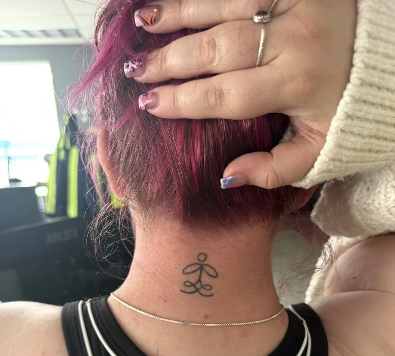 Small fine line tattoo on the back of a neck