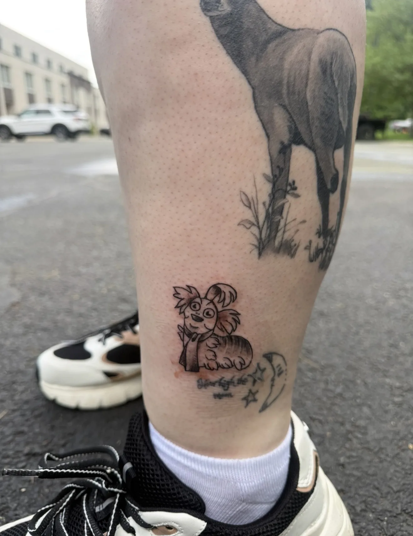 Leg tattoos: a deer, a cartoon pup, and a moon with stars