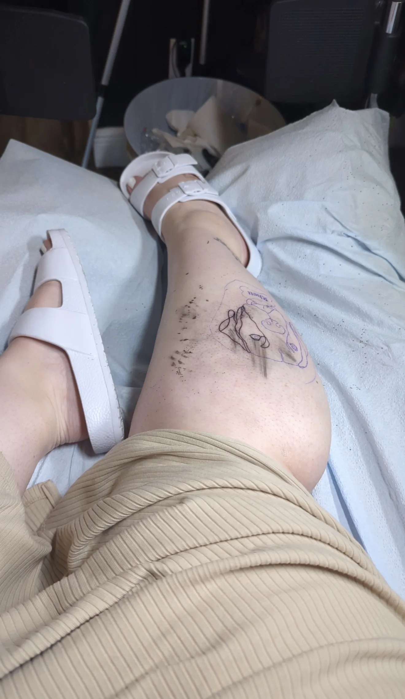 In-progress tattoo stencil of a dog portrait on a leg